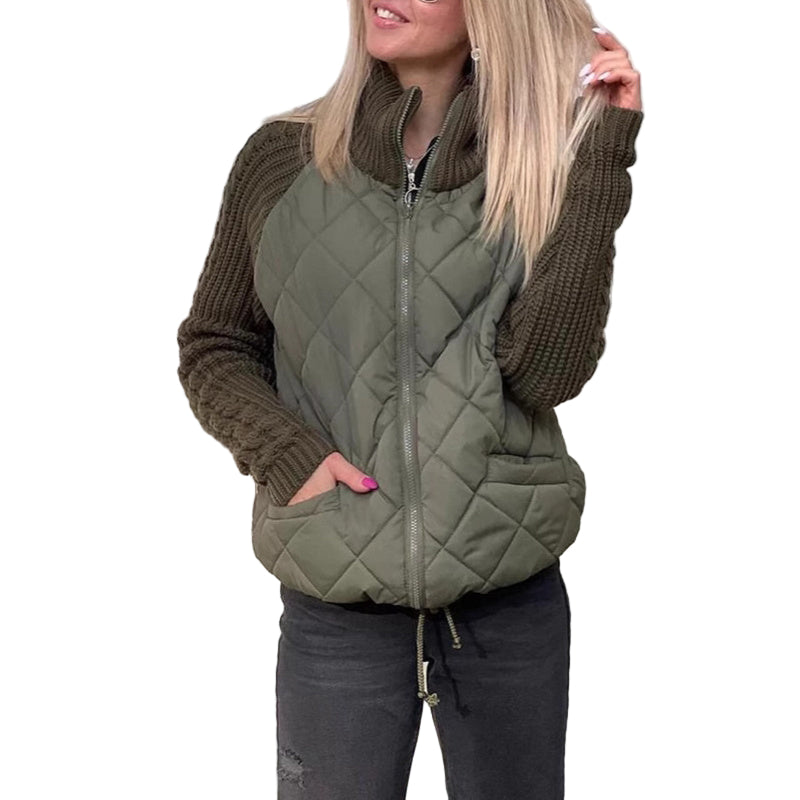 Woman wearing a green quilted vest over a brown sweater against a wooden wall.