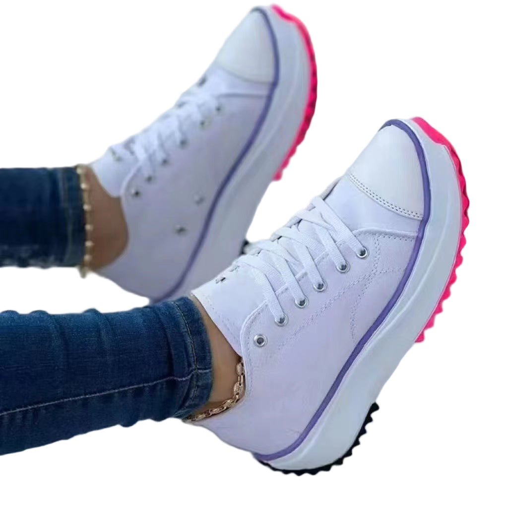 White sneakers with pink soles worn by a person on a light background