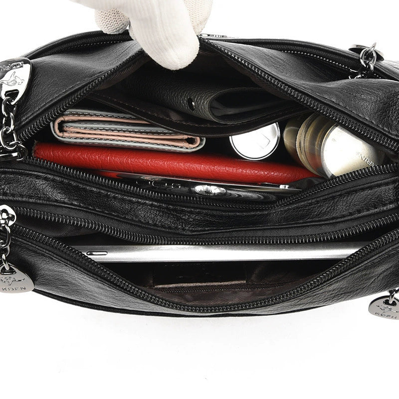 Black leather handbag with compartments open, showing various items inside.