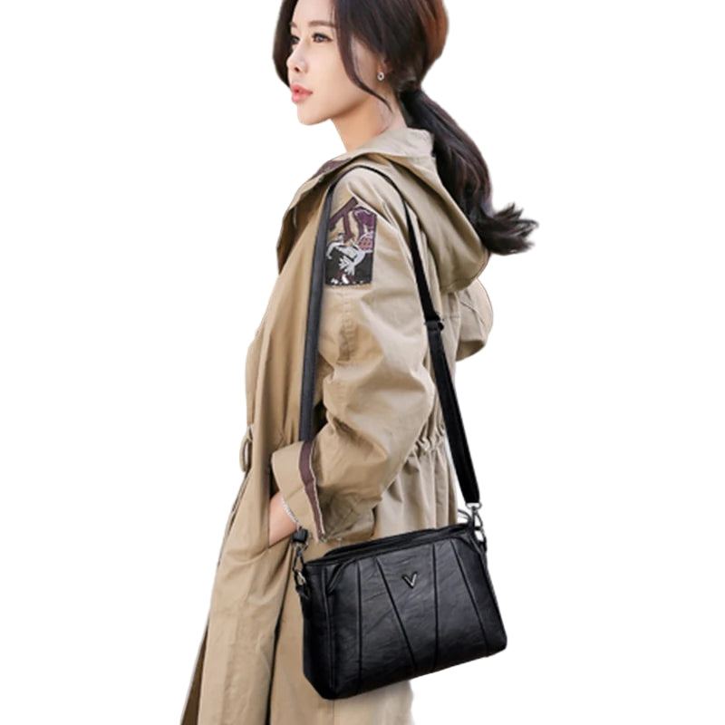 Woman in a beige trench coat carrying a black handbag outdoors.