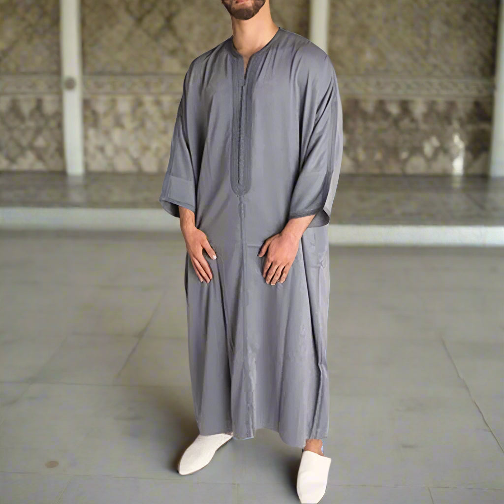 Man wearing a long gray robe against a plain background