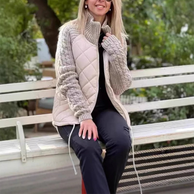Woman sitting on a bench wearing a quilted jacket and gloves outdoors.