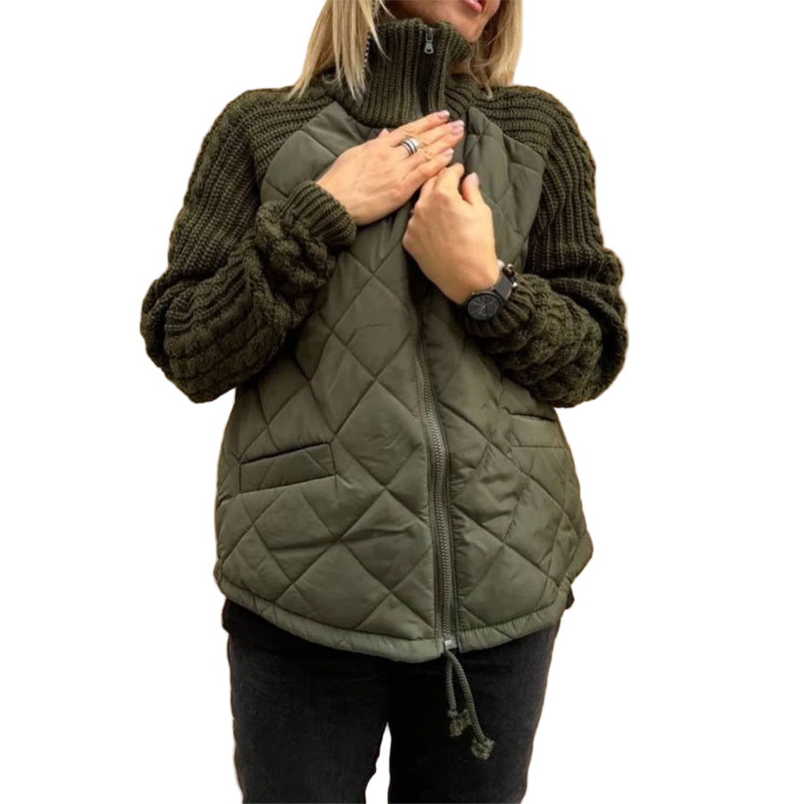 Person wearing a green quilted vest over a dark sweater against a beige wall.
