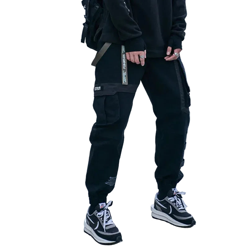 Person wearing black cargo pants and sneakers on a tiled pavement.