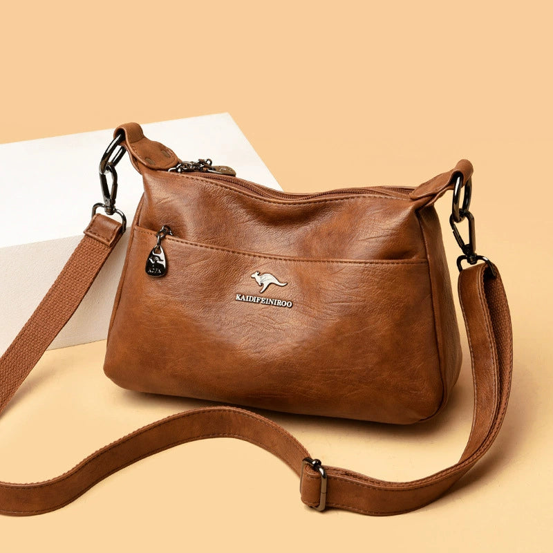 Brown leather handbag with a visible brand logo on a beige background