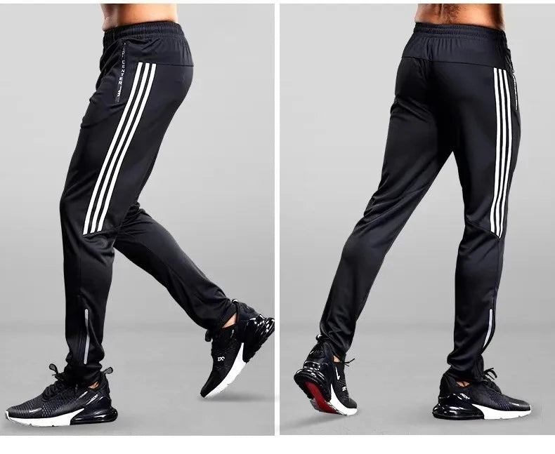 Black athletic pants with white stripes worn by a person on a gray background