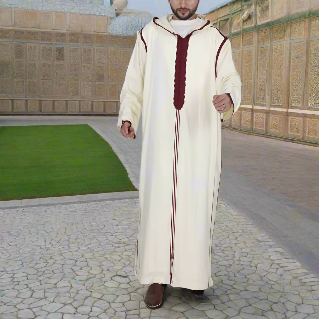 Man wearing a long, cream-colored robe with red accents on a white background