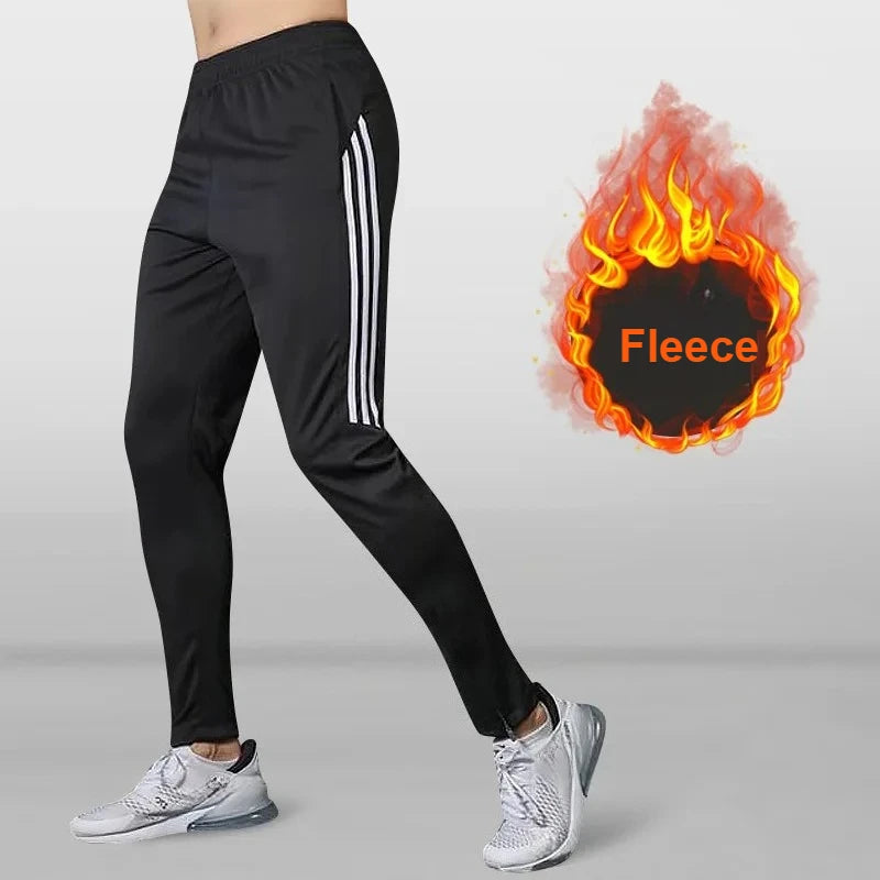 Black athletic pants with white stripes worn by a person, with a fiery 'Fleece' graphic inset.