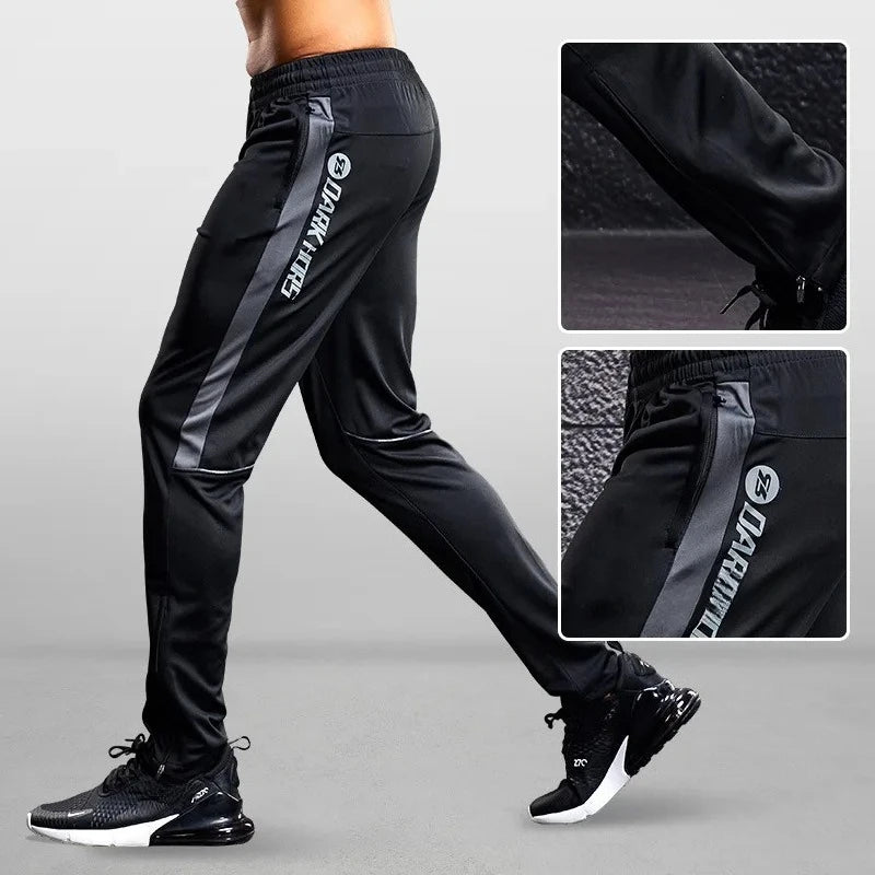 Black athletic pants with gray accents and brand logo on a gray background