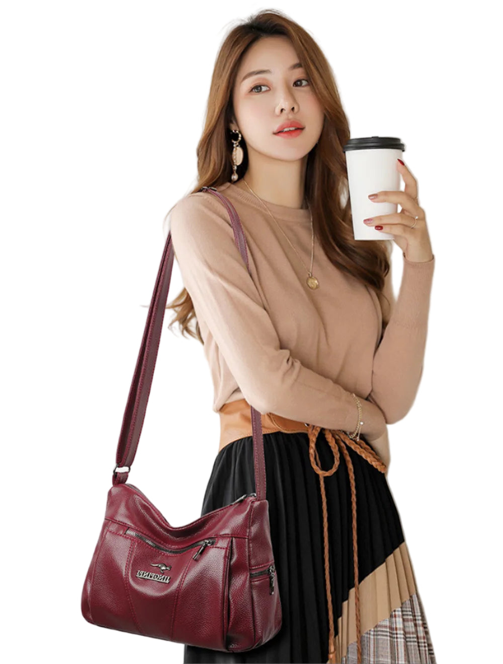 Woman holding a coffee cup and a maroon handbag against a white background