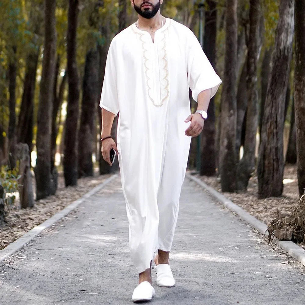 Man in a white outfit walking along a path in a forest