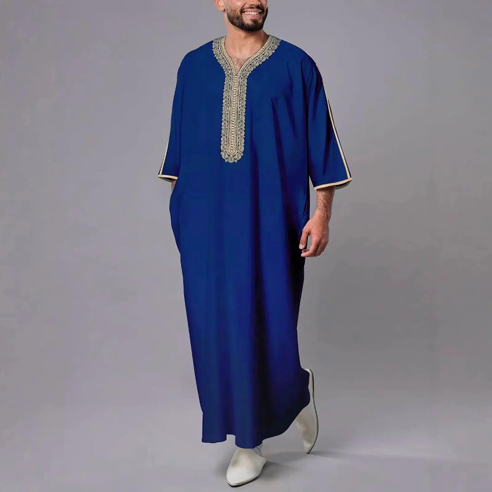 Man wearing a blue embroidered robe against a gray background