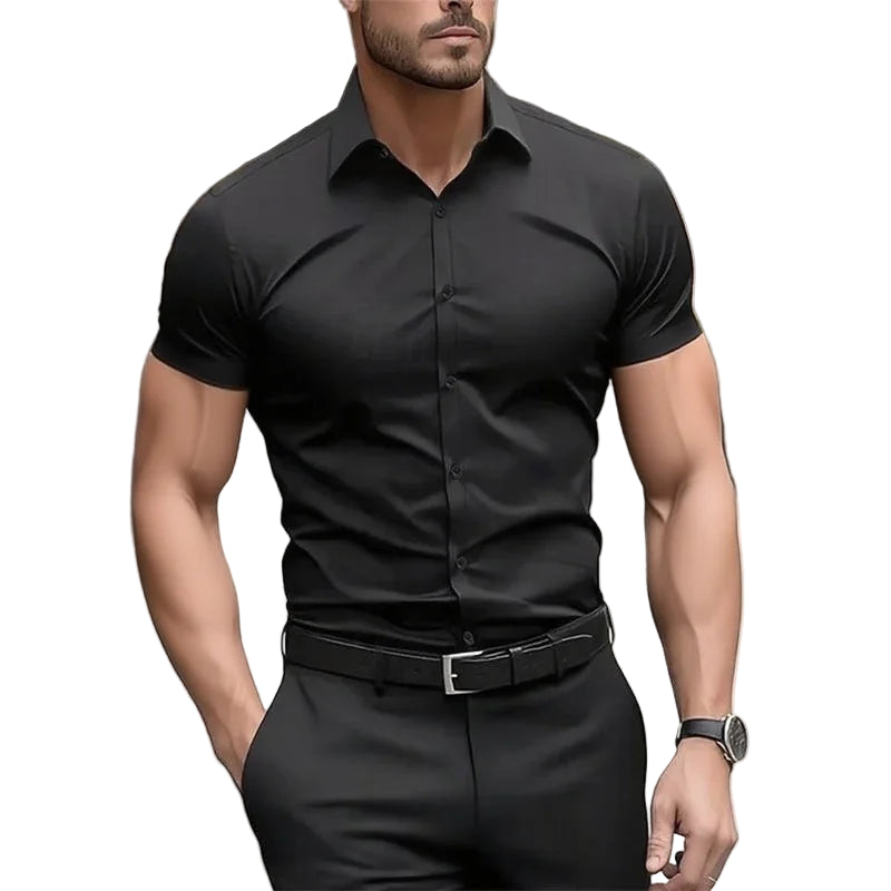 Man wearing a black short-sleeve dress shirt and pants with a blurred background