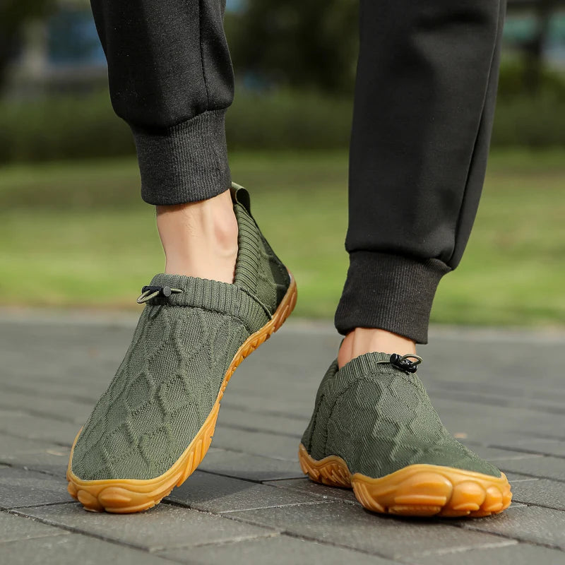 Green shoes with brown soles worn by a person on a paved surface.