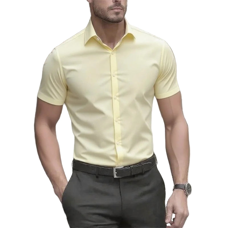 Man wearing a light yellow short-sleeve dress shirt and dark pants outdoors.