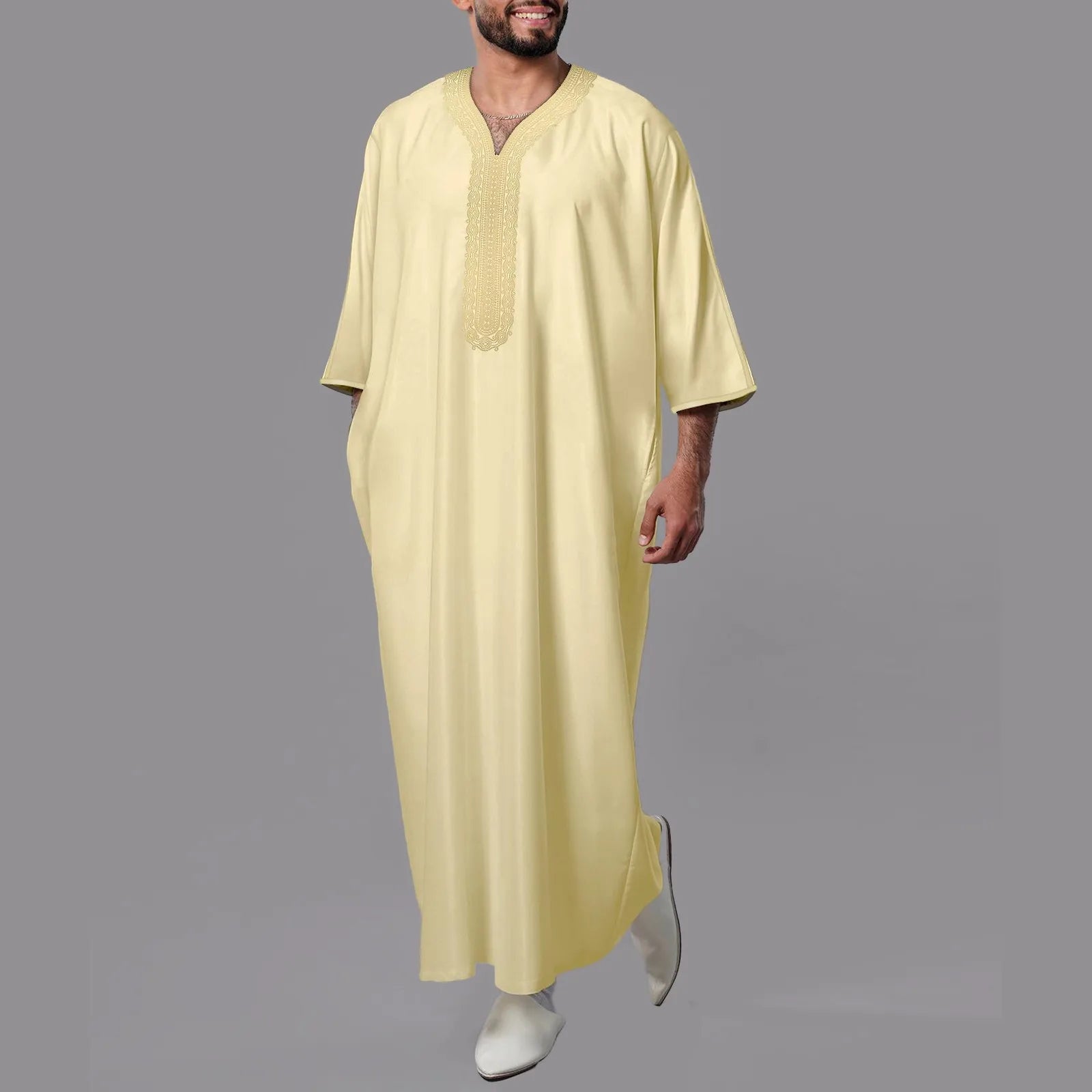 Man wearing a light yellow traditional outfit on a gray background
