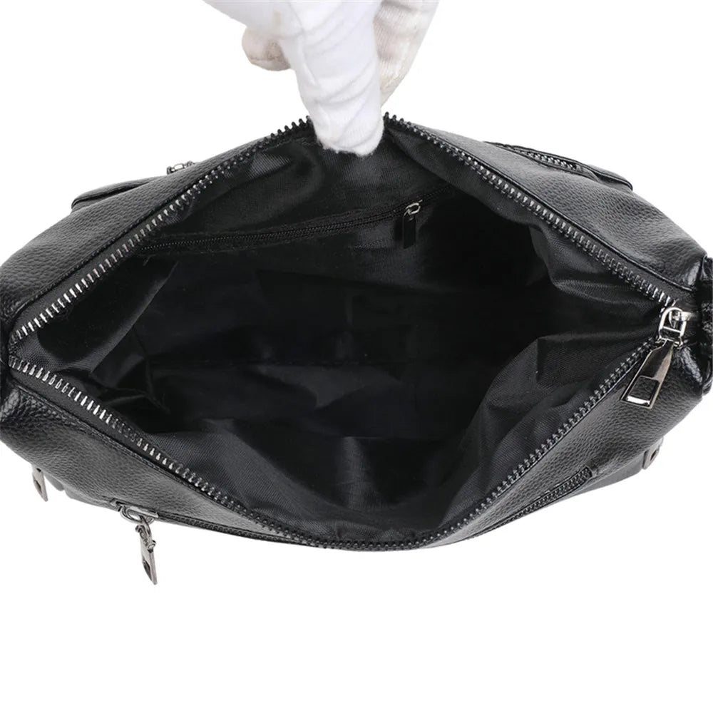 Black leather bag with a gloved hand holding it open on a white background