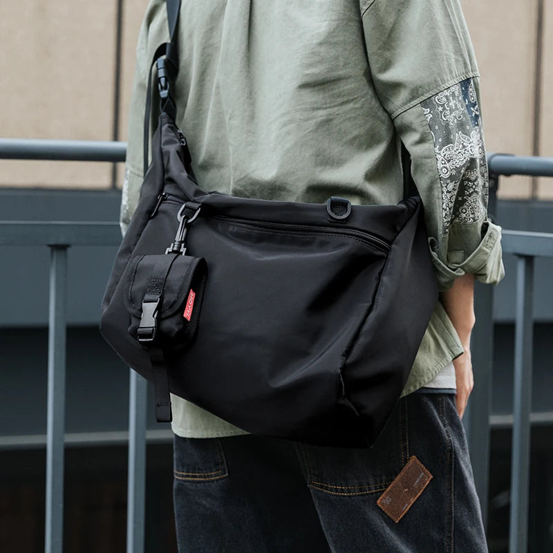 Person wearing a black shoulder bag with a neutral background