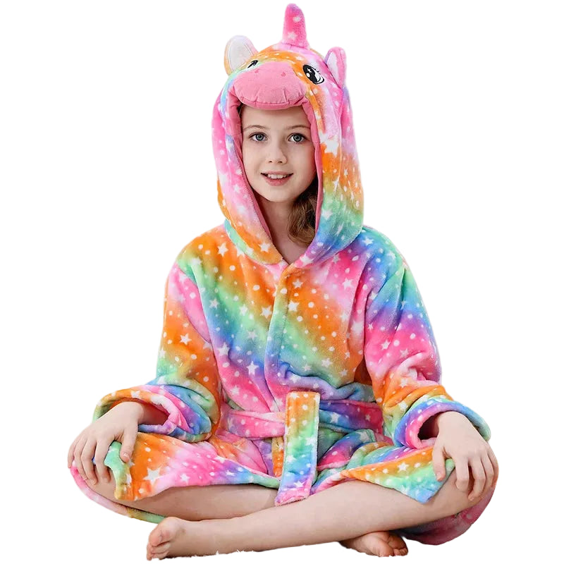Child wearing a colorful unicorn onesie sitting on a couch.