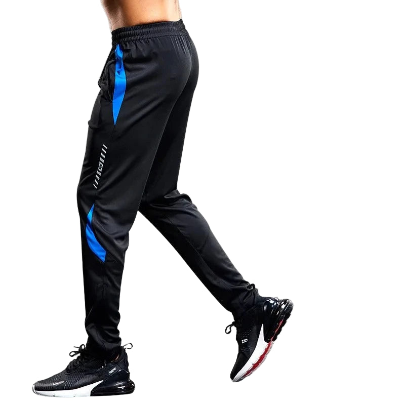 Black athletic pants with blue accents worn by a person on a gray background