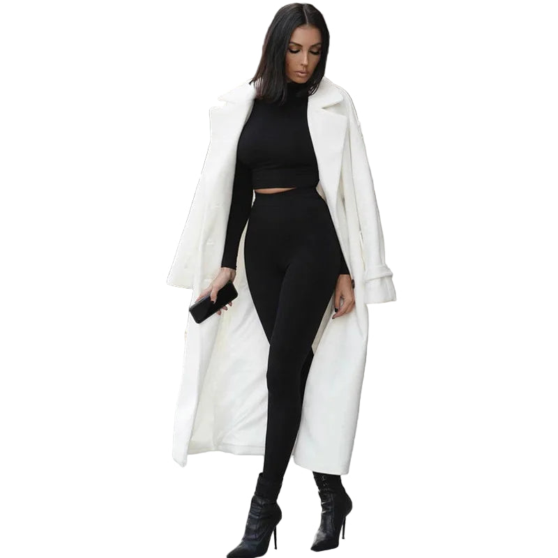 Woman wearing a white coat over a black outfit with high heels on a city street.