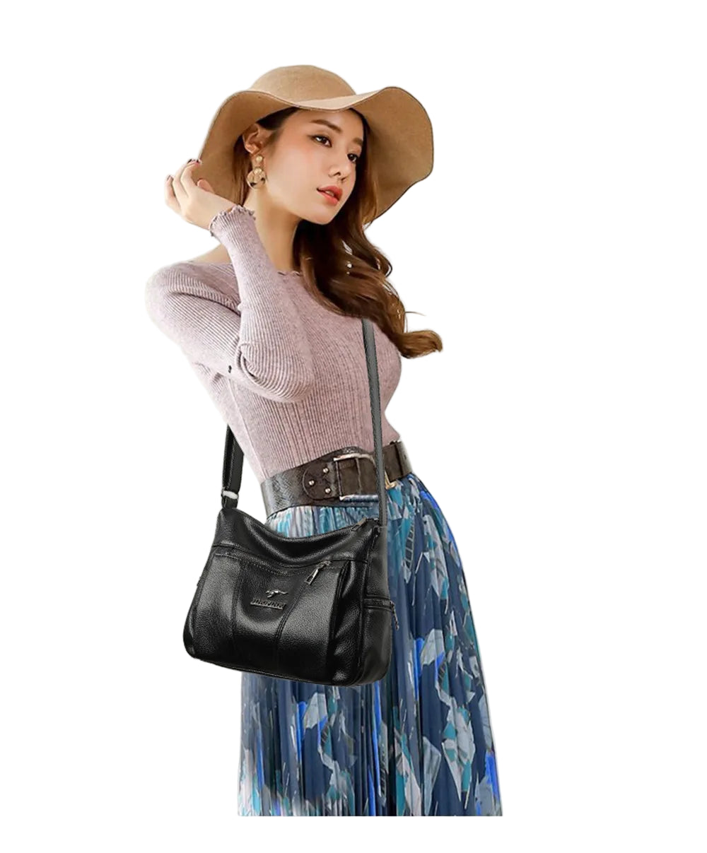 Woman wearing a pink sweater, brown hat, and blue floral skirt with a black bag indoors.