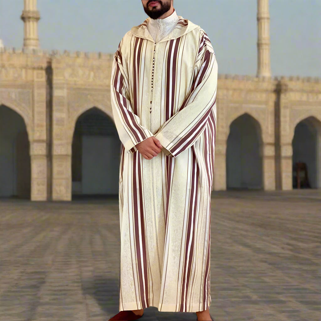 Man wearing a traditional outfit in a room with decorative sofa and wall art.