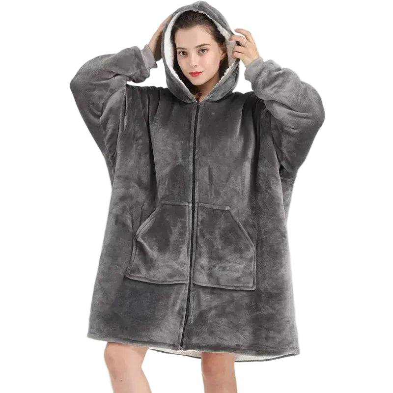 Person wearing a gray fleece poncho with a hood and zipper on a white background
