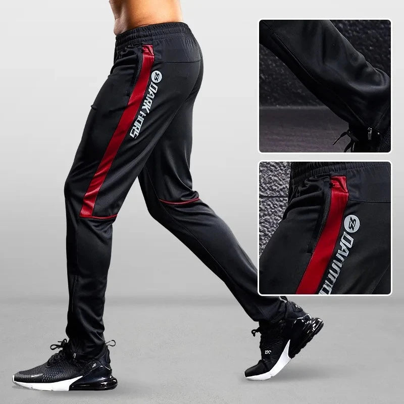 Black jogger pants with red stripes and brand logo on a gray background