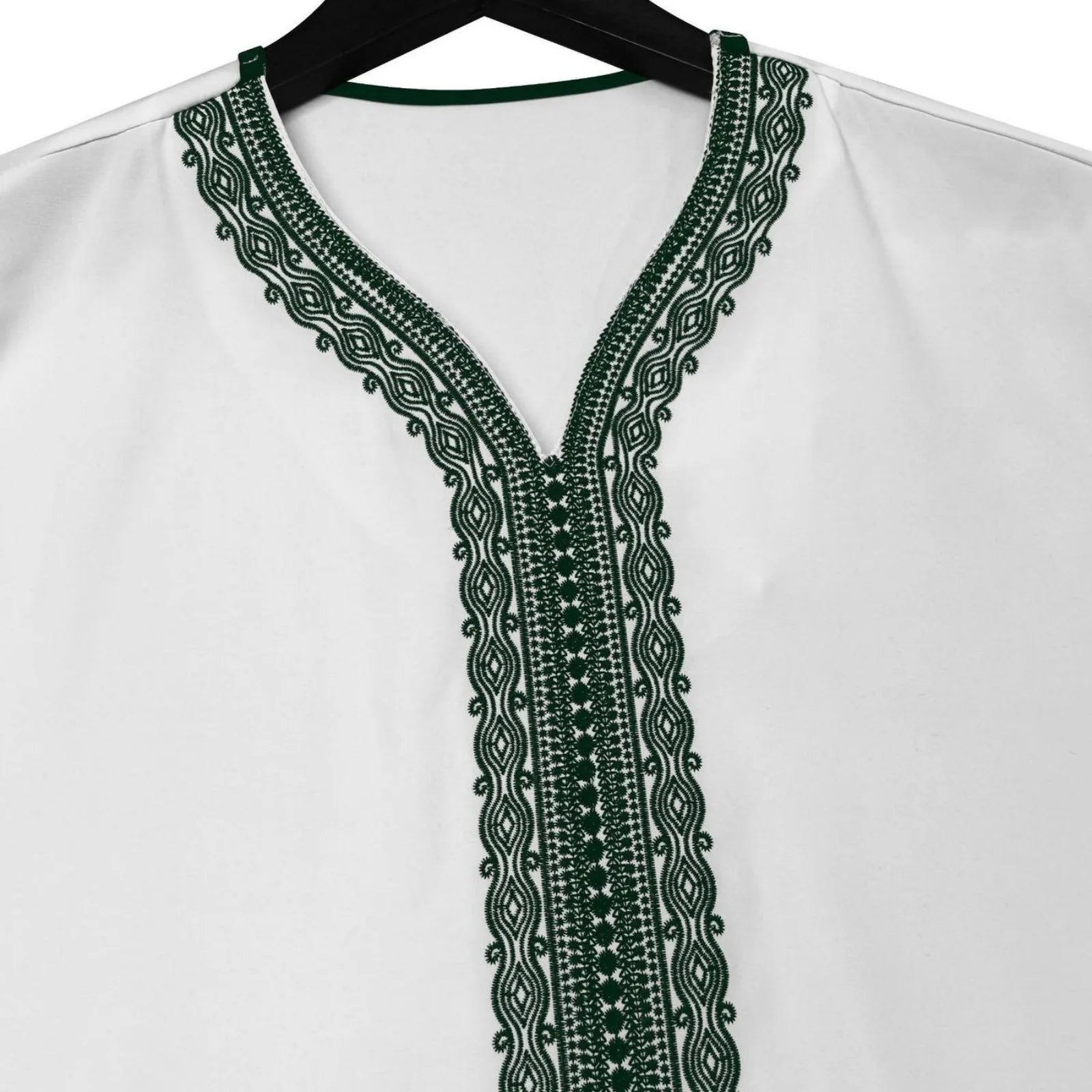 White blouse with green embroidery on a hanger against a white background