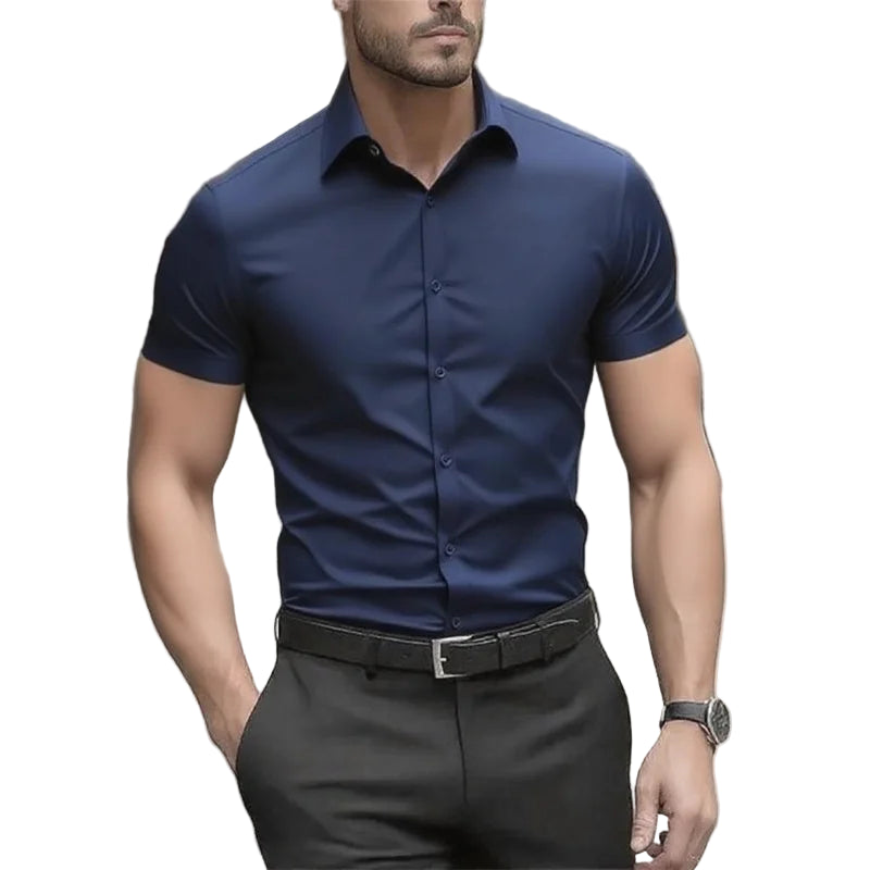 Man wearing a navy blue short-sleeve dress shirt and black pants outdoors.