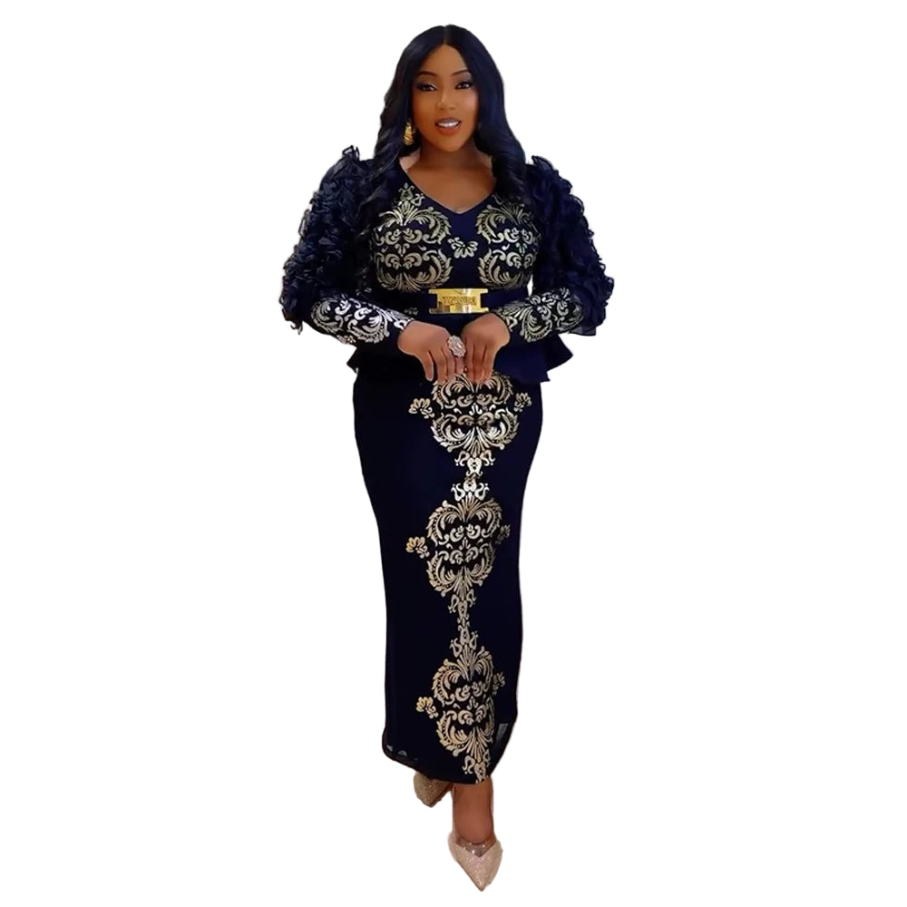 Woman in a black and gold embroidered outfit standing in a modern interior setting.