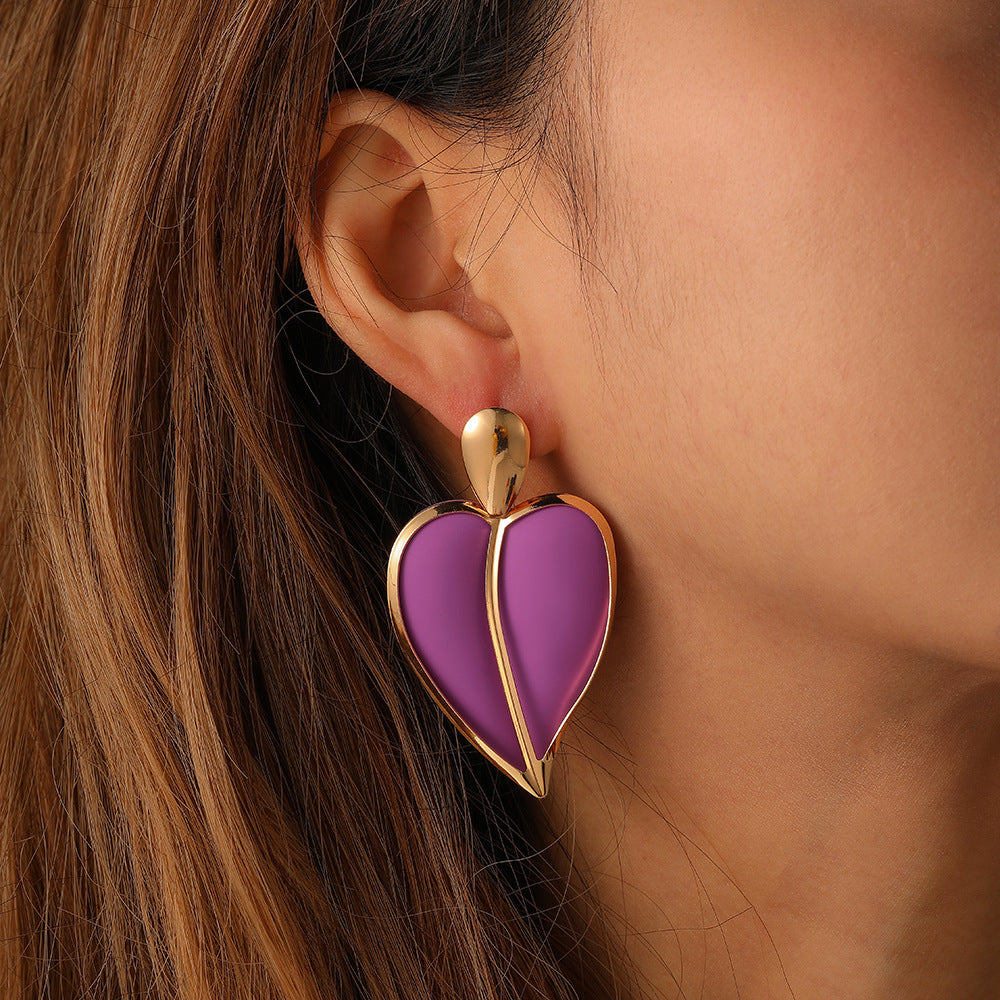 Purple heart-shaped earring on a person's ear with a blurred background