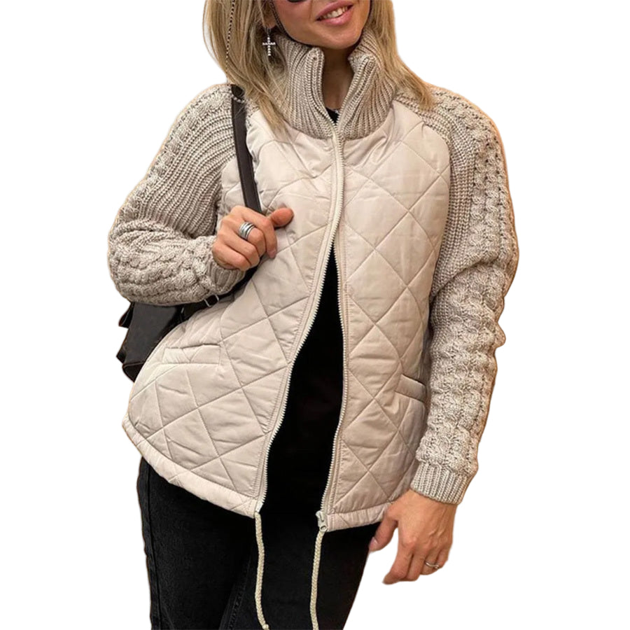 Person wearing a beige quilted jacket with knitted sleeves against a beige wall.