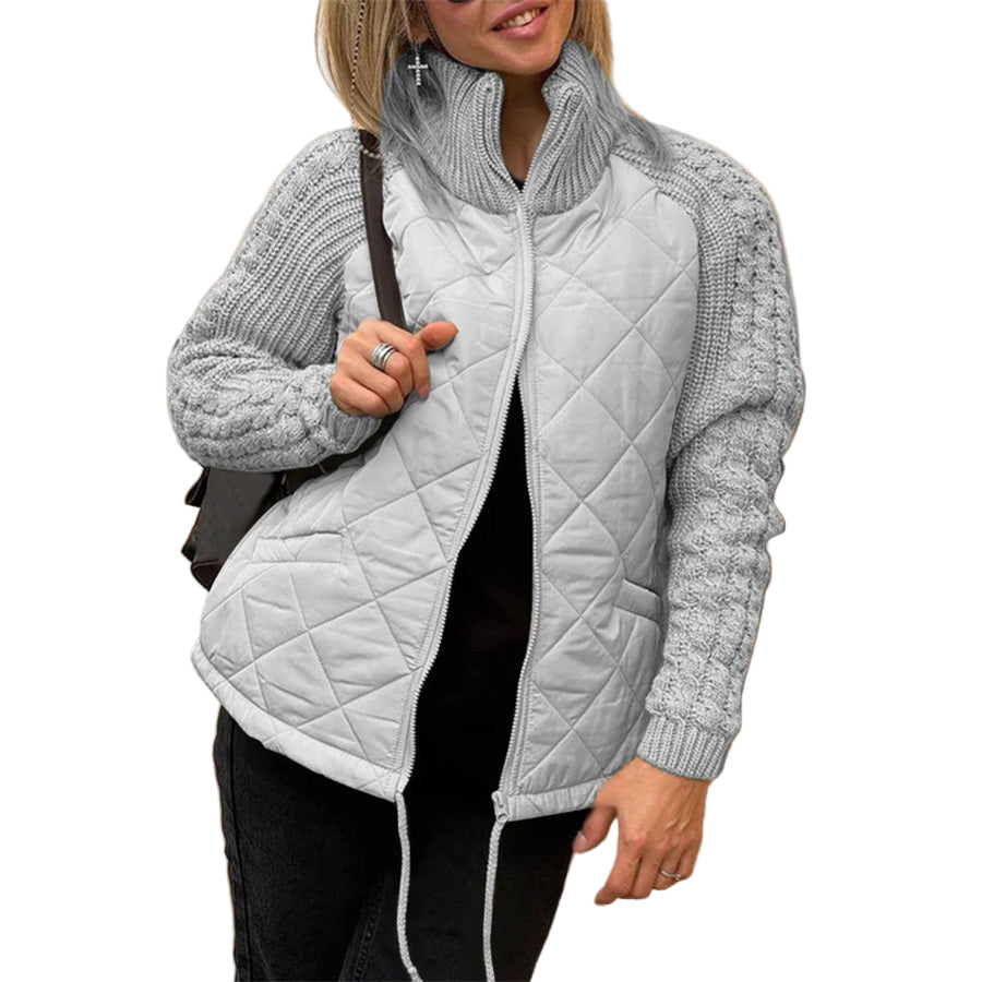 Woman wearing a gray quilted jacket with a beige wall background